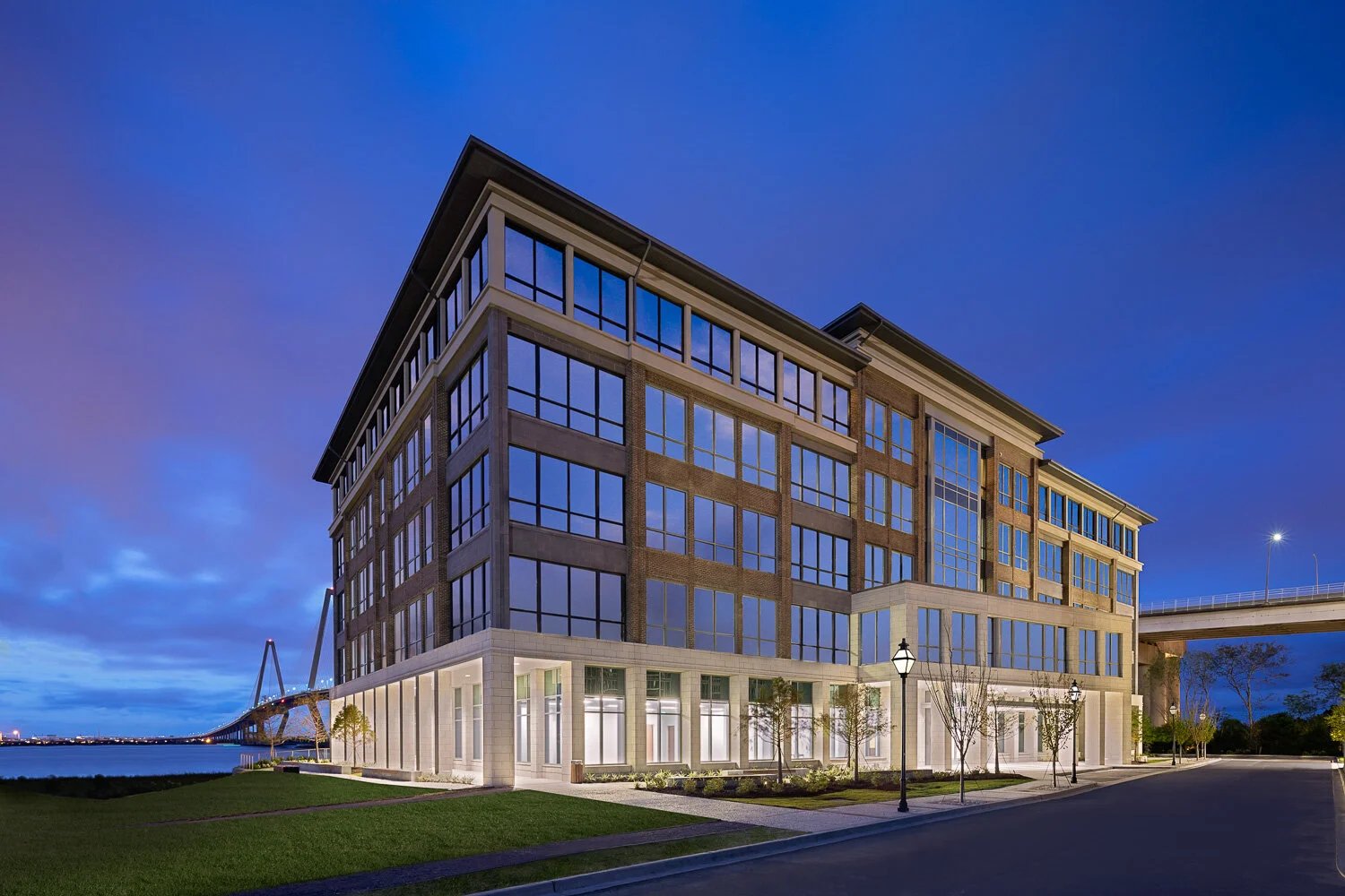 Faucona & Co Charleston office at 75 Port City Landing, Mount Pleasant, South Carolina, with the Arthur Ravenel Jr. Bridge in the background at dusk